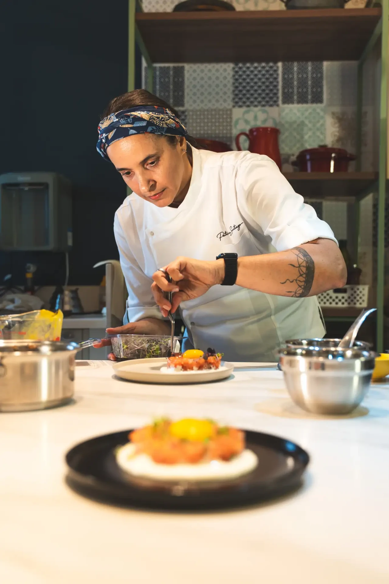 Patricya Santiago finalizando um prato durante uma experiência gastronômica.