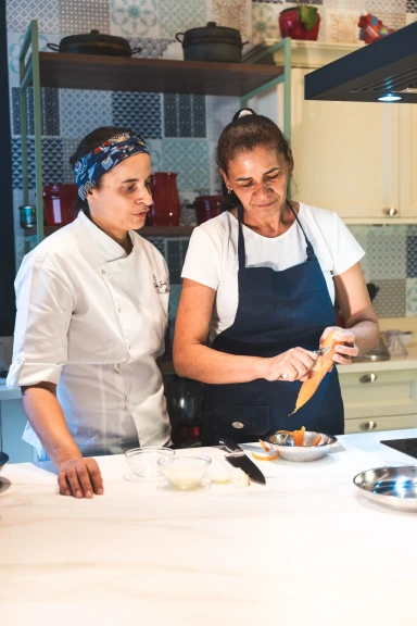 Patricya Santiago orientando uma funcionária durante o preparo de alimentos na cozinha.