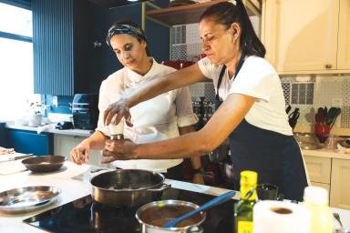 Patricya Santiago acompanhando uma funcionária durante a prática de técnicas culinárias.
